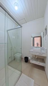a bathroom with a glass shower and a sink at Hotel Hawaii in Colíder