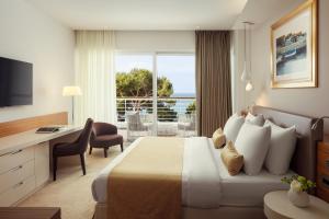 a hotel room with a bed and a desk and a window at Hotel Bellevue in Mali Lošinj