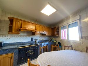 eine Küche mit Holzschränken, einem Tisch und einem Fenster in der Unterkunft Casa Rosiña in Campo Lameiro + 27 Fotos