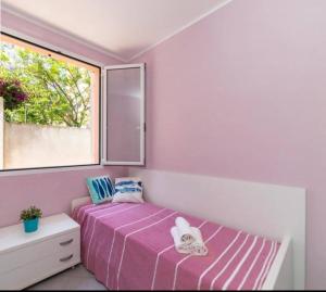 een slaapkamer met een paars bed en een raam bij La casetta rosa in Diano Marina