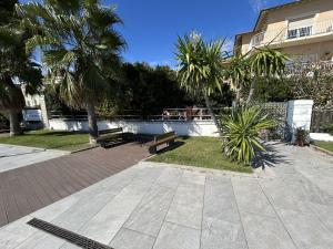 een park met banken en palmbomen naast een gebouw bij La casetta rosa in Diano Marina
