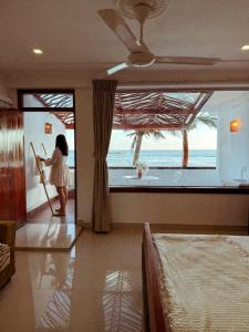 a woman standing in a room looking out at the ocean at Beach House Goviyapana in Ahangama