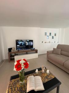 Una sala de estar con un jarrón de flores y un libro. en Le Terrazze della Dolce Casa - Blue Wave - Casa Vacanza a Marina di Ragusa, en Marina di Ragusa 33 fotos más