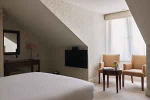 um quarto com uma cama e 2 cadeiras e uma televisão em Fermain Valley Hotel em St Peter Port