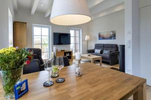 a living room with a wooden table with wine glasses at Haus Dünenperle, Ferienwohnung Dünengras in Wittdün +12 photos