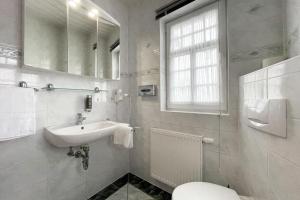 een witte badkamer met een wastafel en een toilet bij Hotel Waldschlösschen und Spezialitätenrestaurant in Oberhof +49 foto's