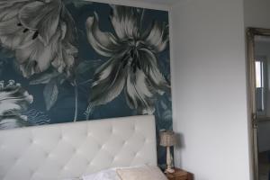 Ein großer Blumendruck an der Wand über einem Bett in der Unterkunft Ferienhaus Kleiner Muck in Glückstadt + 12 Fotos