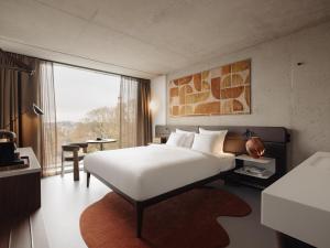 a bedroom with a large white bed and a large window at Hotel V Oosterpark in Amsterdam