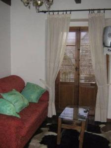 een woonkamer met een rode bank en een tafel bij Casa del Herrador I in Carrascal del Río