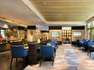 Un restaurante con sillas y mesas azules y un bar. en Fairmont Beijing, en Beijing