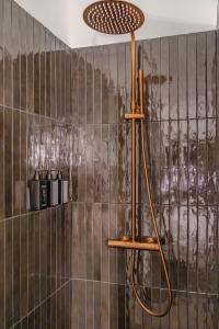 een douche in een badkamer met een bruine tegelmuur bij Luxurious Penthouse Lumina - Fire place, Pool and Spa in Val Thorens