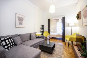 un soggiorno con divano grigio e sedie gialle di Houseloft Bianca Vision a Salonicco