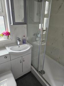 ein weißes Badezimmer mit Waschbecken und Dusche in der Unterkunft Blue light studio in Cardiff