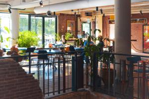 a restaurant with tables and chairs and people sitting at tables at De Groene Afslag Kunsthotel in Bussum