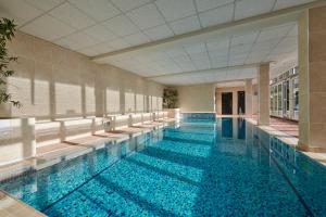 a large swimming pool with blue water in a building at Fermain Valley Hotel in St. Peter Port