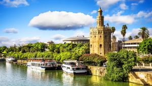 a clock tower next to a river with boats at TAYP Sol 120 in Seville