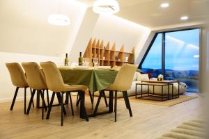 a dining room with a green table and chairs at The Sky Hill - luxury chalet in Kupres