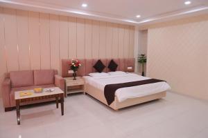 a bedroom with a large bed and a couch at Avadh Hotel & Banquets in Bareilly