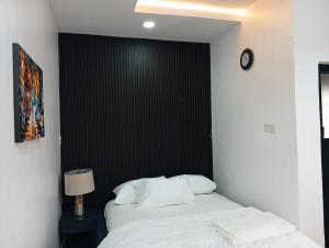 een slaapkamer met een bed met witte lakens en een zwarte muur bij Heirloom Luxury Hotel and Apartments in Maiyegun