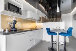 a kitchen with white cabinets and blue bar stools at Village Naturiste R4N - Le Bocca Port Nature Coursive Luxe in Cap d'Agde +9 photos