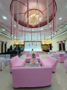 a large room with pink couches and a chandelier at Avadh Hotel & Banquets in Bareilly