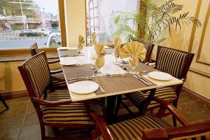 ein Holztisch mit Stühlen und ein Tischset mit Tellern in der Unterkunft Heaven Hotel in Lahore
