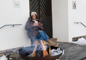 Una mujer está sentada junto a un fuego. en Berghotel Hoher Knochen - Ruhe & Natur, en Winterberg 58 fotos más