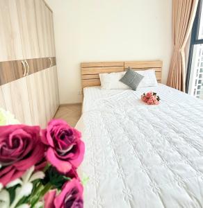 a bedroom with a white bed with pink roses at Căn hộ 1 phòng ngủ MASTERI VINHOMES GRAND PARK Quận 9 in Long Bình