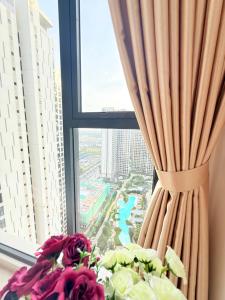 a window with a curtain and a bouquet of flowers at Căn hộ 1 phòng ngủ MASTERI VINHOMES GRAND PARK Quận 9 in Long Bình