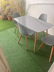 a white table and two chairs on a green carpet at Chez Permal in Saint-Pierre