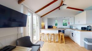a kitchen with white cabinets and bar stools at C25 Weir View, Riviere Towans in Hayle +7 photos