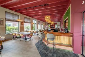 ein Restaurant mit Bar sowie Tischen und Stühlen in der Unterkunft Groepsaccommodatie De Landerij in Scherpenzeel + 64 Fotos