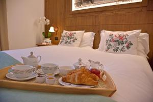 a tray of food on a bed with tea and croissants at Hotel Beau Sejour in Etroubles