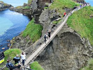 a group of people crossing a suspension bridge over a cliff at Clare Escape Ballycastle - Luxury town centre apartment, walk to beach & harbour, near Giants Causeway in Ballycastle