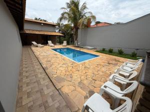 a group of white chairs sitting next to a swimming pool at Carneiro in Boituva