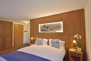 エトロウブレスにあるホテル ボー セジュールの木製のヘッドボードが付いた白いベッドのある寝室