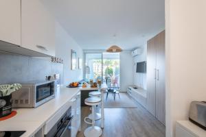 a kitchen with white cabinets and a counter with stools at Étoile de Mer * wifi * Parking * Clim * Central * in La Grande-Motte