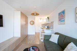 a living room with a green couch and a kitchen at Étoile de Mer * wifi * Parking * Clim * Central * in La Grande-Motte