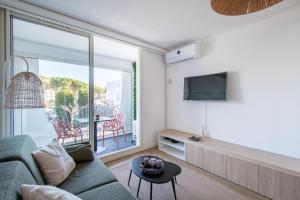 a living room with a couch and a tv at Étoile de Mer * wifi * Parking * Clim * Central * in La Grande-Motte