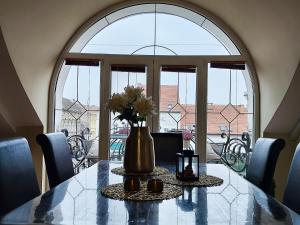 a dining room table with a vase with flowers on it at Apartmani Sunset in Slavonski Brod