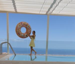 een vrouw die in een zwembad loopt met een donut in haar hand bij MEDITERRANEAN SEASONS, VILLA MEDITERRANEA Taormina, Private Pool & Sea View in Taormina +17 foto's