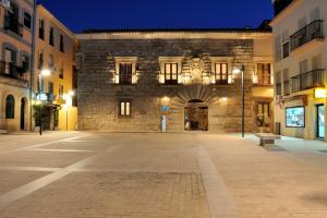 an empty street in front of a stone building at night at Palacio Carvajal Girón in Plasencia
