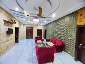 a living room with red chairs and a ceiling fan at Hotel Pak Continental Multan in Multan