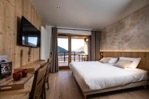 a bedroom with a bed and a desk with a television at Chalet Valora in Le Grand-Bornand +91 photos