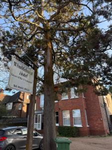 a sign in front of a tree in front of a building at Wimblehurst Hotel in Horsham
