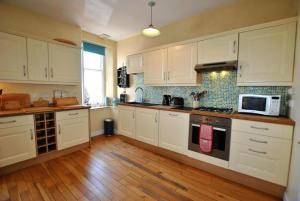 een keuken met witte kasten en een kookplaat oven bij Bayview - St Monans in Saint Monance