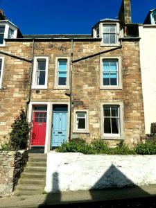 een stenen huis met een rode en blauwe deur bij Bayview - St Monans in Saint Monance