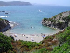 een groep mensen op een strand in het water bij Aghinas in Bosa