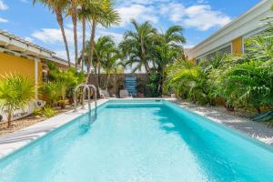een zwembad voor een huis met palmbomen bij Barefoot Bonaire in Kralendijk