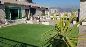 a garden with a green lawn in front of a building at Signature Lodges in Islamabad